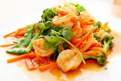 Delasia_Food Impact. Auf dem Bild ist ein asiatisches Gericht zu sehen, welches aud bunten asiatischen Gemüse und Garnelen besteht. Es ist in apetitlich angerichtet mit einer süß-sauren Soße und Koriander als Garnitur.