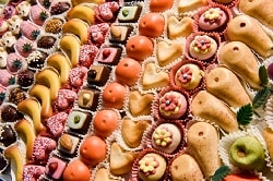 ISM-Süßwaren Messe_auf dem Bild ist mini Marzipan-Obst zu sehen. Dabei sind von links: Erdbeeren, Bananen, Mandarinen, Birnen, Äpfel. Das Bild ist sehr farbenfroh.