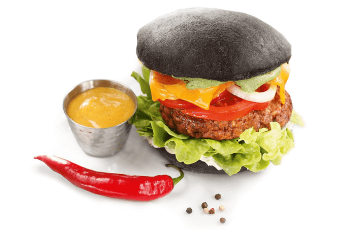 Ein Rezept für einen Black Burger Classic von Edna mit schwarzem Burger Brot, Bulette, Zwiebeln, Tomaten, Salat, Käse und einer Chilischote