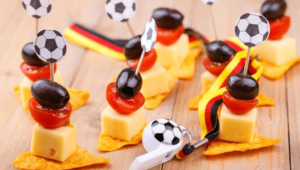 Kleine Snacks in Form von Käsestücken, mit Tomatenscheiben und Trauben auf einem Zahnstocher