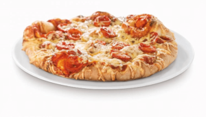 Die Pizza mit Currywurst von Perplex ist auf dem Foto auf einem weißen Teller zu sehen.