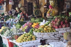 Obst und Gemüsestand in Südostasien. Gestapelte Papaya, Mango, Granatäpfel uvm Früchte in Holzschiffchen.