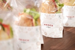 Rausch verpackungen: Aus der Makroperspektive aufgenommene Sandwiches in weißer rausch verpackung. Das obere drittel der Verpackung ist durchsichtig, so dass der Snack zu sehen ist.