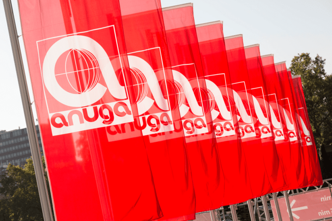Auf dem Foto sind mehrere rote Fahnen hintereinander zu erkennen, die das Logo der Branchenfachmesse Anuga haben.