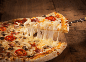 Eine Pizza belegt mit Käse, Salami, Tomaten und Pilzen, dessen Käse zerläuft