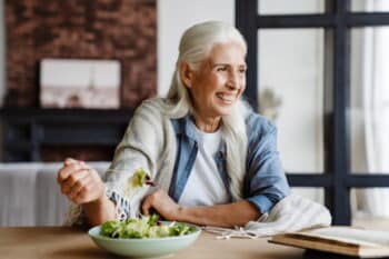 Ältere Frau isst Salat und liest ein Buch