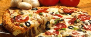 Eine Pizza belegt mit Käse, Salami, Tomaten und Pilzen, dessen Käse zerläuft