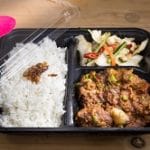 Food Impact_Delasia_Auf dem Bild sieht man China food in einer to go Verpackung welche einer dreier Aufteilung hat. Diese besteht aus Reis, Gemüse und Fleisch in Soße.