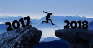 Jahresrückblick 2017_Auf dem Bild sieht man eine Klippe über die ein Mann springt. links steht in großen Zahlen 2017 und rechts 2018. Der man springt von links nach rechts. Die Farben sind in blaitönen gehalten und schwarz.