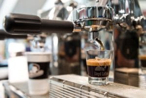 Deutsche Kaffeemeisterschaften auf der Gastro Ivent 2017. Auf dem Bild ist ein Siebträger zu sehen an dem gerade aus einem einer Sieb ein Espresso gezogen wird. Er läuft in ein durchsichtiges kleines Glas.