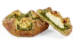 Auf dem Bild erkennt man das Spinat-Rocotta-Nest des französischen Herstellers Delifrance. Der Blätterteig-Snack ist von der Seite abgebildet. Eins von zwei Snacks ist in der Mitte durchgeschnitten und auf der andere angelehnt worden, damit der Betrachter des Bilder die Spinat, Ricotta Füllung des Nestes erkennt. Das Nest ist gold-braun gebacken.