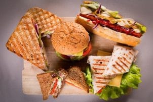 Hot Dog, Burger, Wraps und Sandwiches auf einer Holzplatte