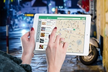 Weibliche Hände, die ein iPad halten. Auf dem iPad ist eine Karte mit Navigation zu Cafés und Restaurants zu sehen.