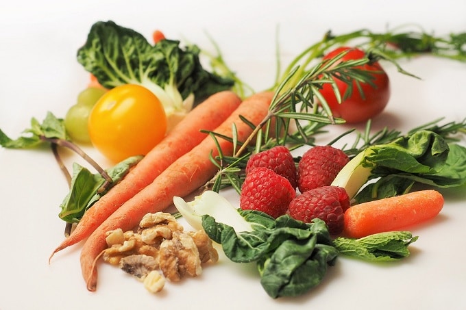 Auf dem Bild sind Karotten, Himbeeren, Weintrauben und Salatblätter zu sehen.