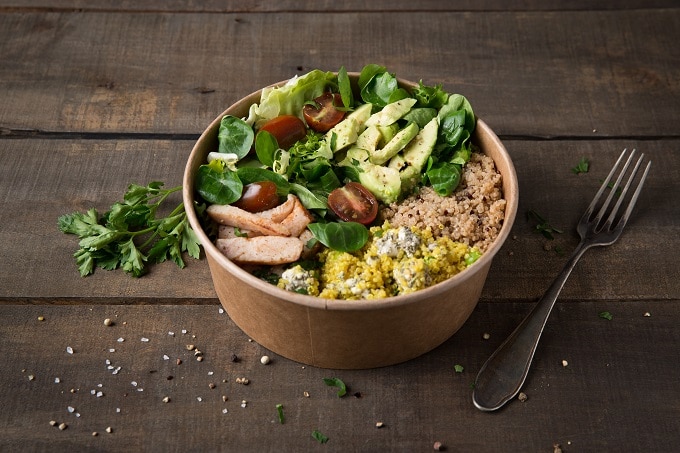Auf dem Bild ist ein Salat in einer Kartonschale von Bionatic zu sehen. Der Salat besteht unter anderem aus Tomaten, Salatblättern, Fleisch und Gurken.