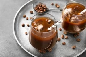 Gläser mit Cold Brew Coffee und Kaffebohnen daneben
