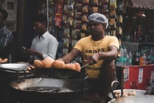 Indischer Verkäufer frittiert Teigbällchen