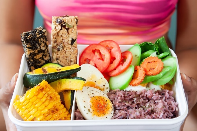 Gesunde Lunchbox mit Gemüse wie Avocado, Mais und Eier