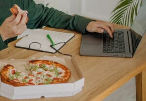 Pizza im Karton auf einem Schreibtisch im Homeoffice / snackconnection