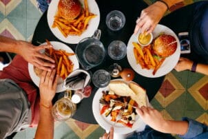 Tisch mit Pommes, Burgern, Sandwich und Gemüse von oben fotografiert / snackconnection