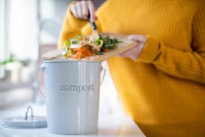 Mensch schmeißt Lebensmittelreste in Eimer zu Hause in der Küche / snackconnection