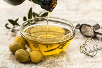 Olivenöl wird aus einer Flasche in eine Schale gegossen / snackconnection