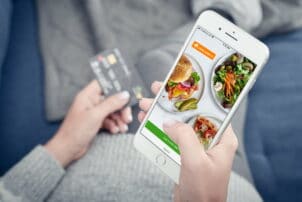 Smartphone mit geöffneter App von Lieferando und Kreditkarte im Hintergrund / snackconnection