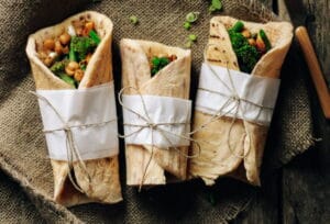 Vegane Wraps mit Kichererbsen in Papier umwickelt / snackconnection