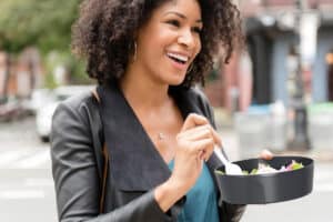 Frau isst Salat im Mehrwegbehälter