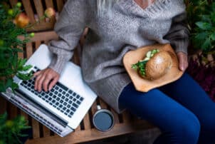 Frau mit Laptop essen vegan Burger