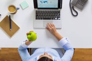 Studie Snacking Berufstätige Arbeitsplatz Frau isst Apfel am Computer