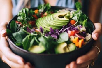 Frau hält vegane Bowl mit Avocado