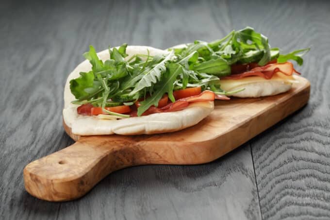 Rezept: Pizza-Sandwich mit Basilikum-Pesto, Rucola, Tomaten und Käse.